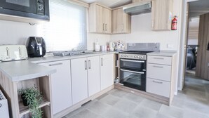 Una cocina moderna con armarios blancos, microondas, tostadora, hervidor y horno.