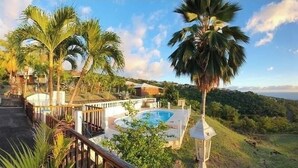 A pool area with a view of the ocean and hills. - Sea view bungalow (Bouillante)
