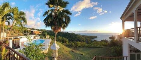 A pool area with a view of the ocean and hills.