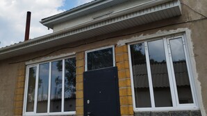 A building with a black door, large windows, and a brick facade. - Travel Around Guest House (Kochkor)
