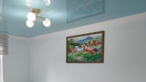 A bedroom with a bed, a nightstand, a rug, and a painting on the wall. - Travel Around Guest House (Kochkor)