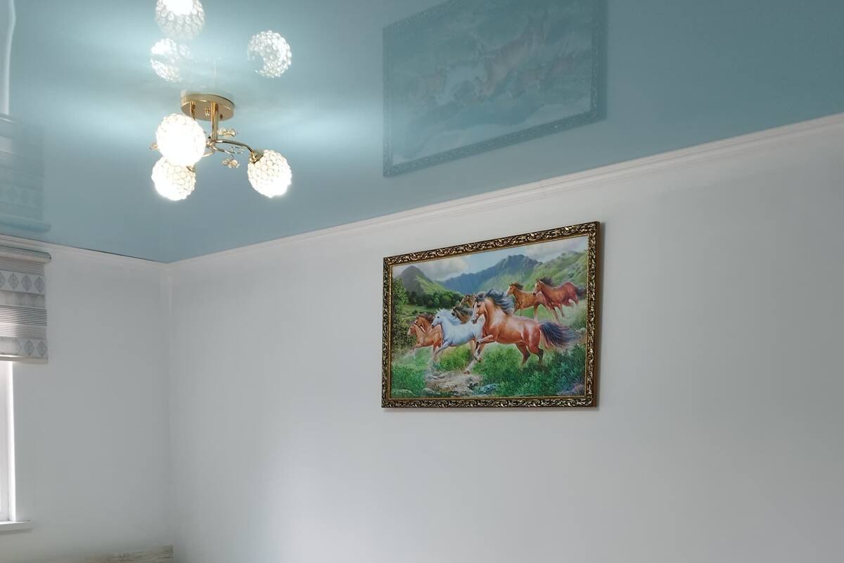 A bedroom with a bed, a nightstand, a rug, and a painting on the wall.