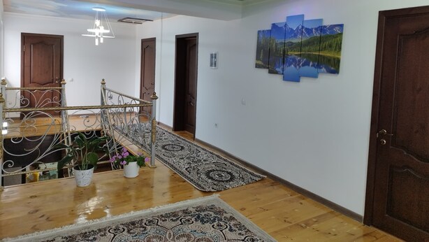A spacious hallway with a wooden floor, a metal railing staircase, and a green ceiling. - Travel Around Guest House (Kochkor)