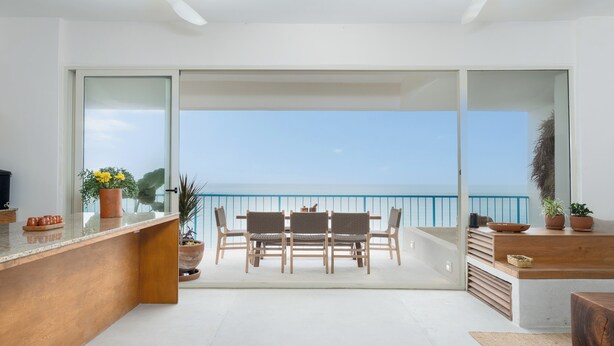 A balcony with a view of the sea, a dining table with chairs, and potted plants. - Oceanfront 2-bedroom luxury at La Escondida - Relax & Enjoy! (Puerto Escondido)
