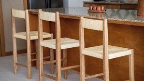 A kitchen with three wooden chairs with woven seats and a granite countertop. - Oceanfront 2-bedroom luxury at La Escondida - Relax & Enjoy! (Puerto Escondido)