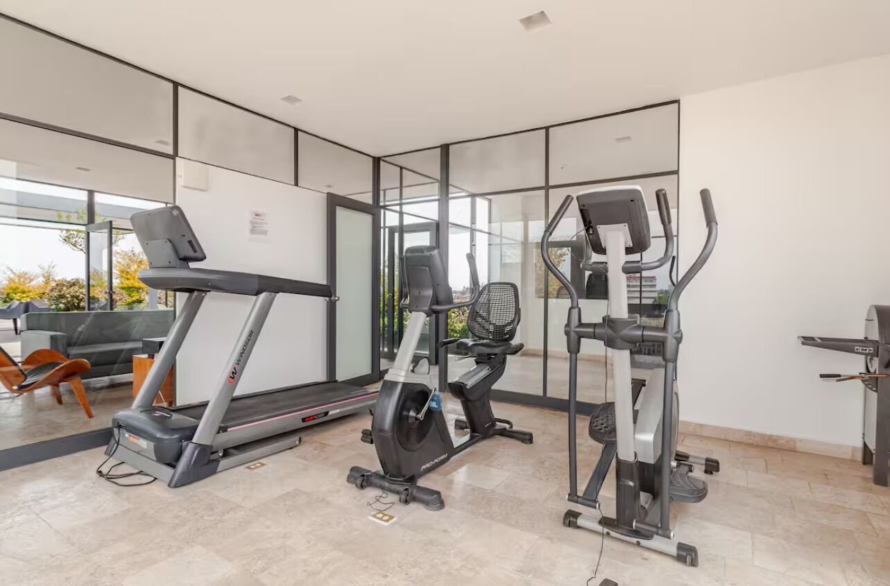 A modern gym with a treadmill, elliptical, and stationary bike.