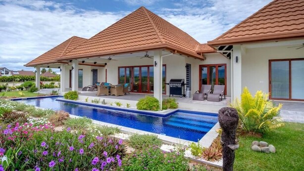 A modern house with a swimming pool, patio furniture, and a well-maintained garden.
