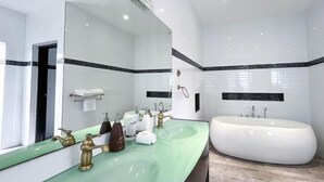 A modern bathroom with a large mirror, two sinks, a bathtub, and a towel rack.
