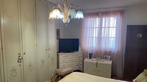 A bedroom with a bed, a dresser, a wardrobe, and a chandelier. - Apartment - Sleeps 5, Balcony, Wifi, Parking (Stazzema)