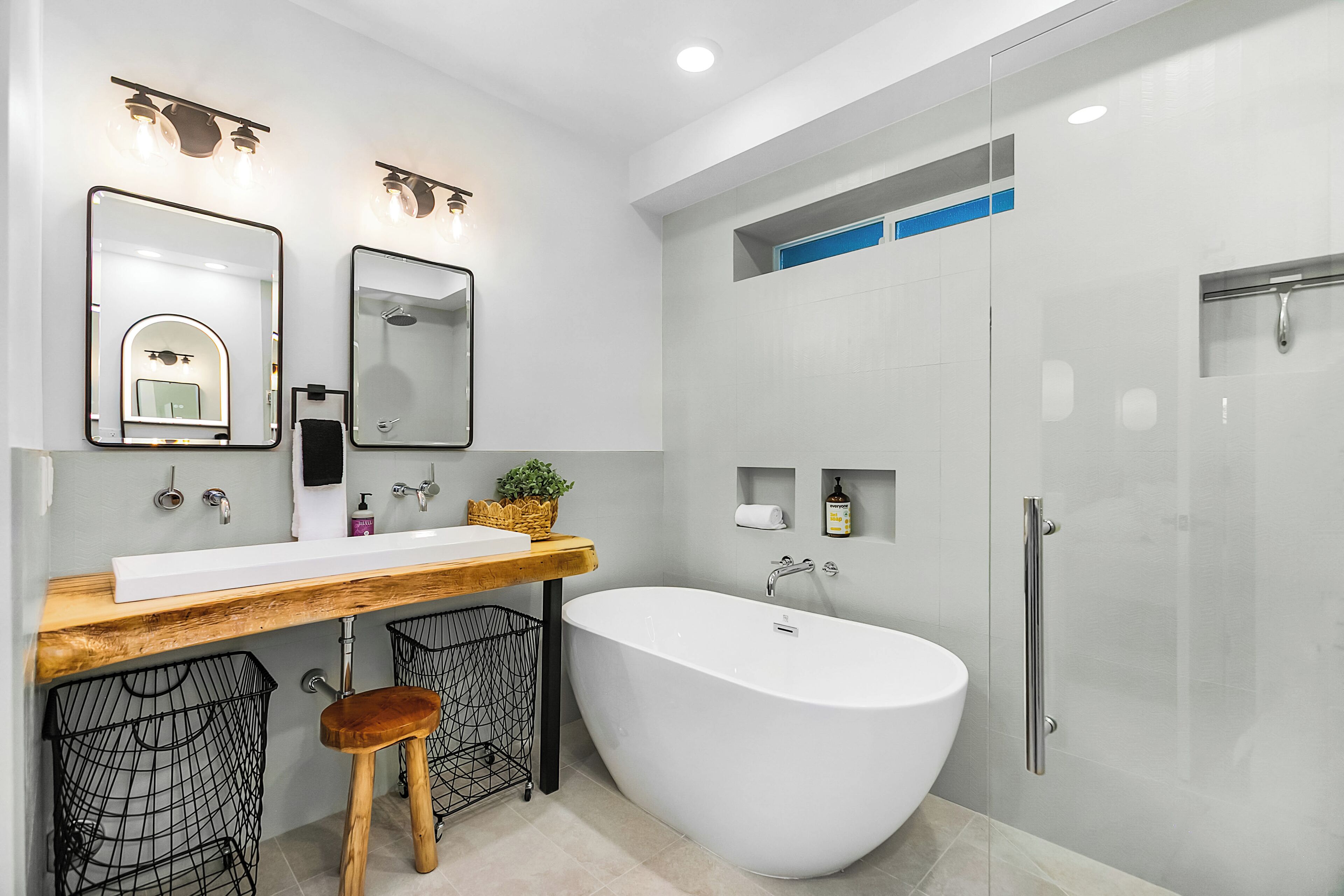 A modern bathroom with a freestanding bathtub, a wooden vanity, and a glass-enclosed shower area.