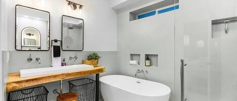 A modern bathroom with a freestanding bathtub, a wooden vanity, and a glass-enclosed shower area.