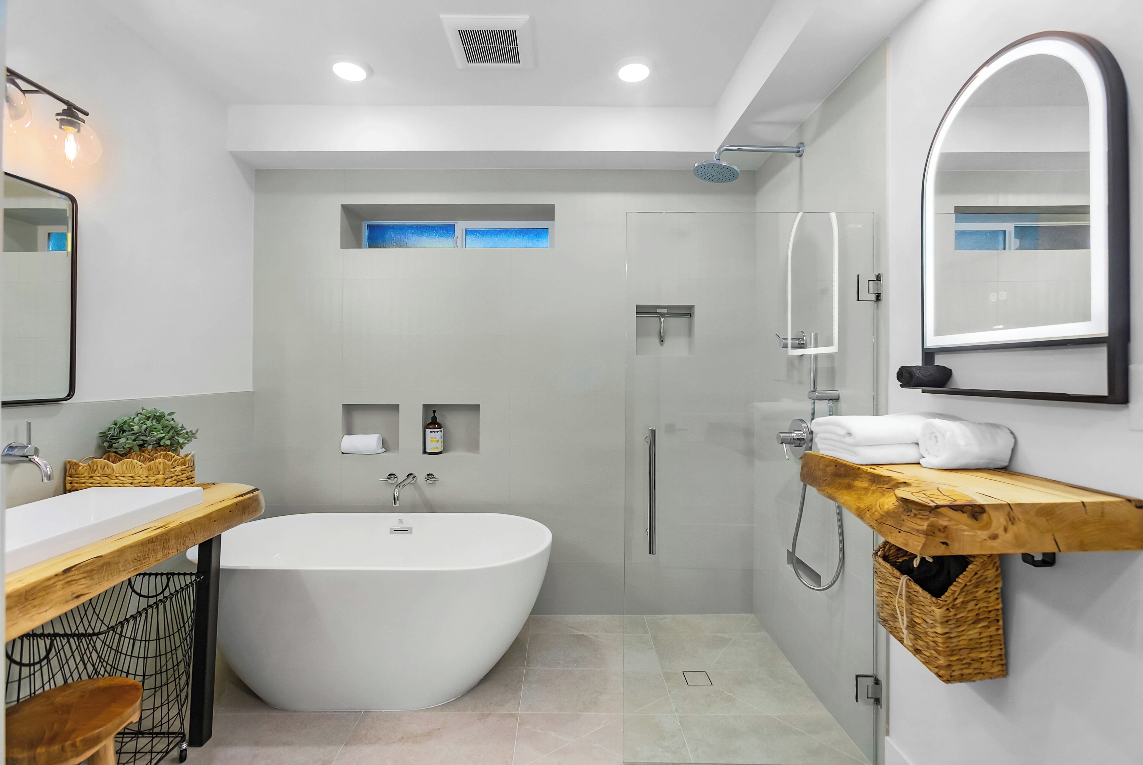 A modern bathroom with a freestanding bathtub, a glass-enclosed shower, and a wooden vanity.