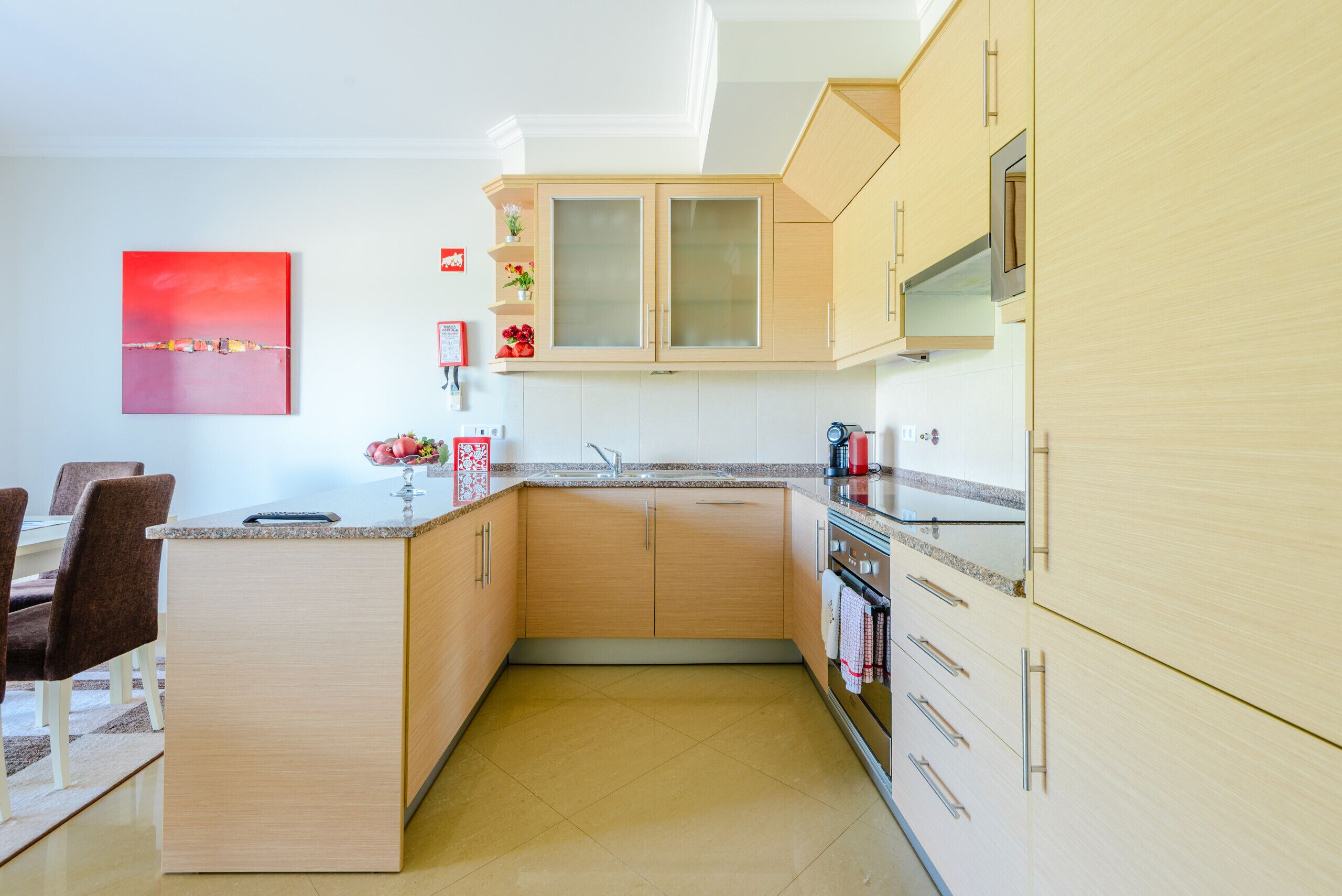 A modern kitchen with a central island, wooden cabinets, and a granite countertop.