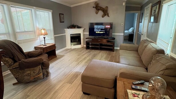 A living room with a fireplace, a television, a ceiling fan, and a sofa.