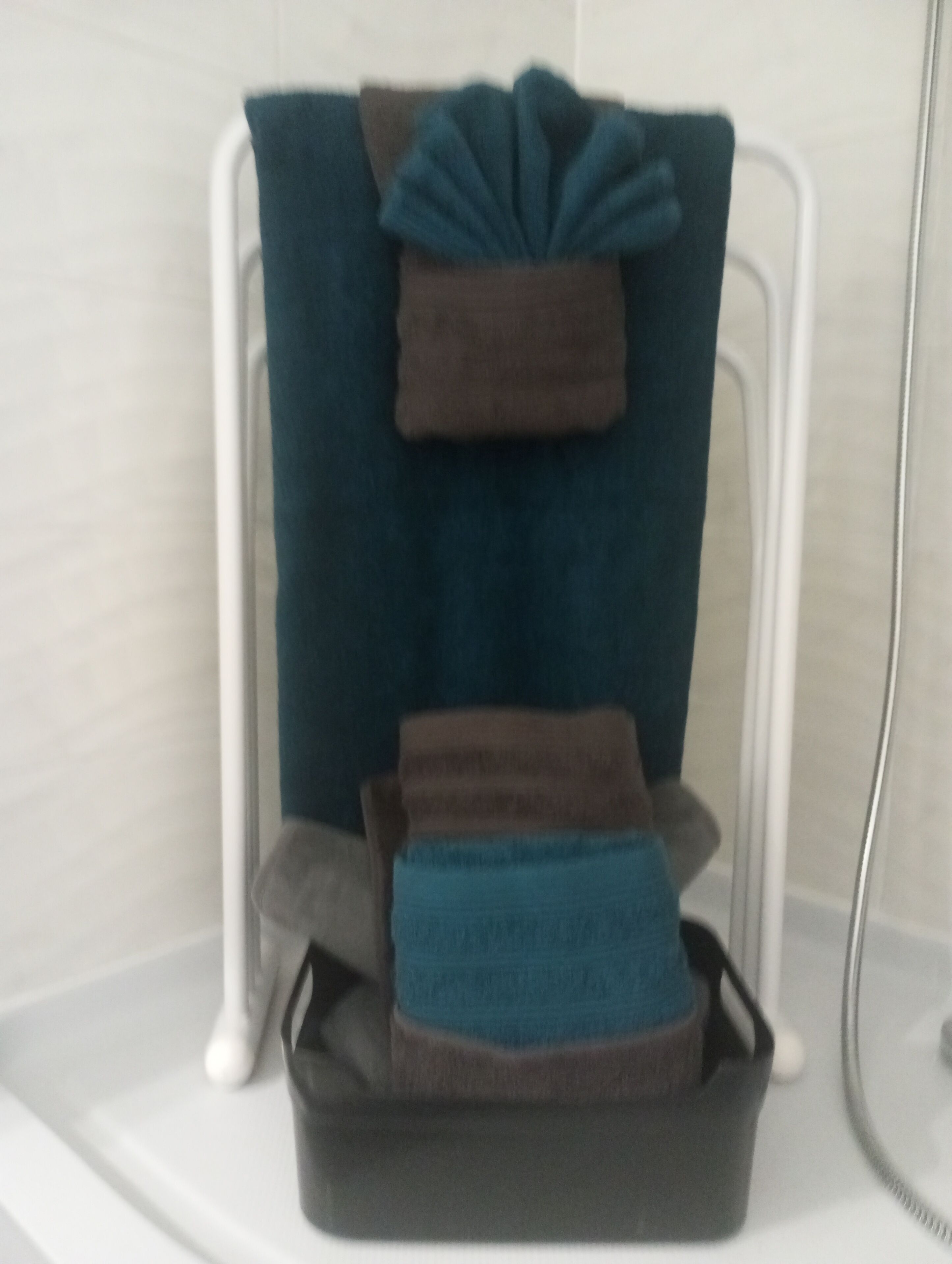Un bagno con una vasca da bagno bianca, un portasciugamani con due asciugamani e un tappetino da bagno nero.
