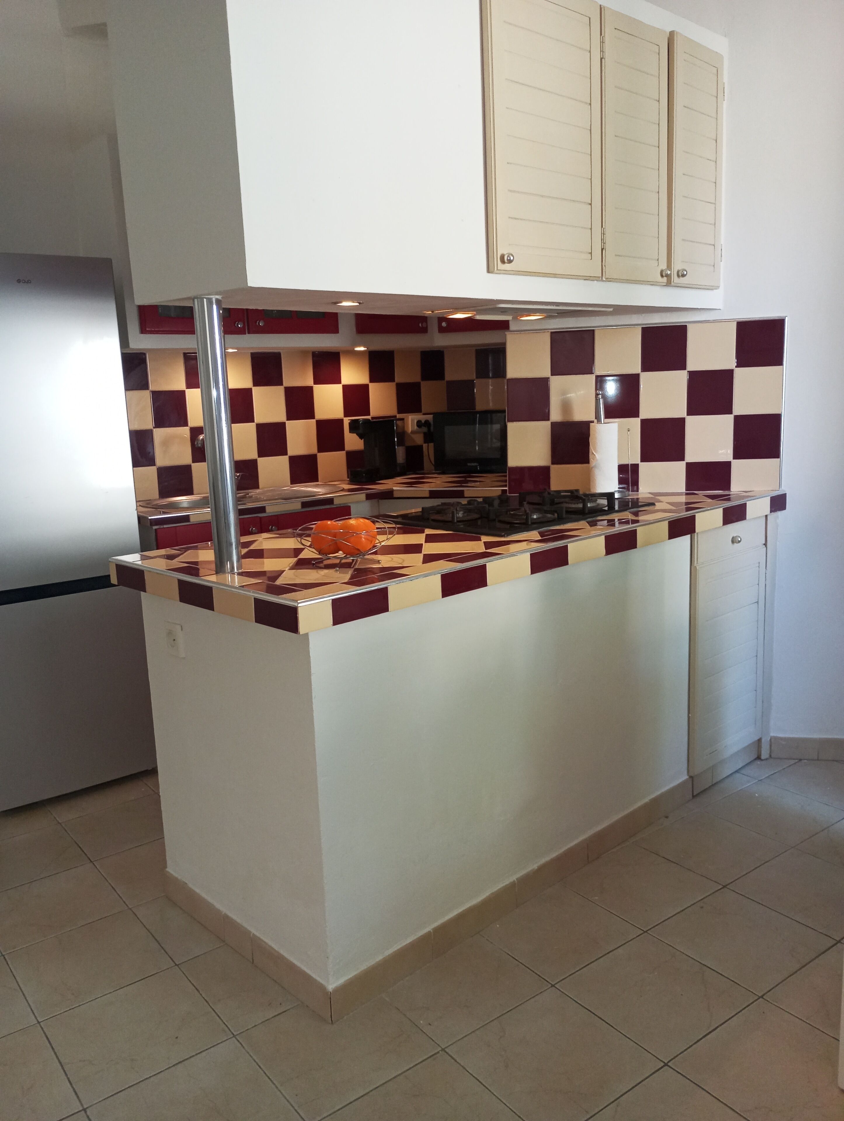 A kitchen with a checkered backsplash, a central island, a refrigerator, and a microwave.