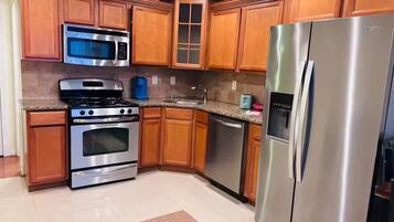 A kitchen with wooden cabinets, a stainless steel refrigerator, a microwave, an oven, and a dishwasher.