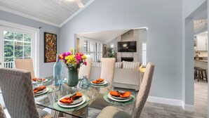 A dining area with a glass table, cushioned chairs, and a vase of flowers.