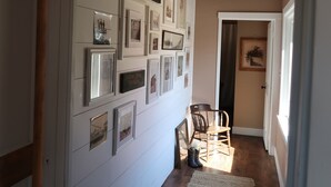 Un couloir avec des tableaux encadrés accrochés au mur, un plancher en bois et un tapis.