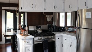 Une cuisine moderne avec des meubles blancs, des appareils électroménagers en acier inoxydable et un plancher en bois.