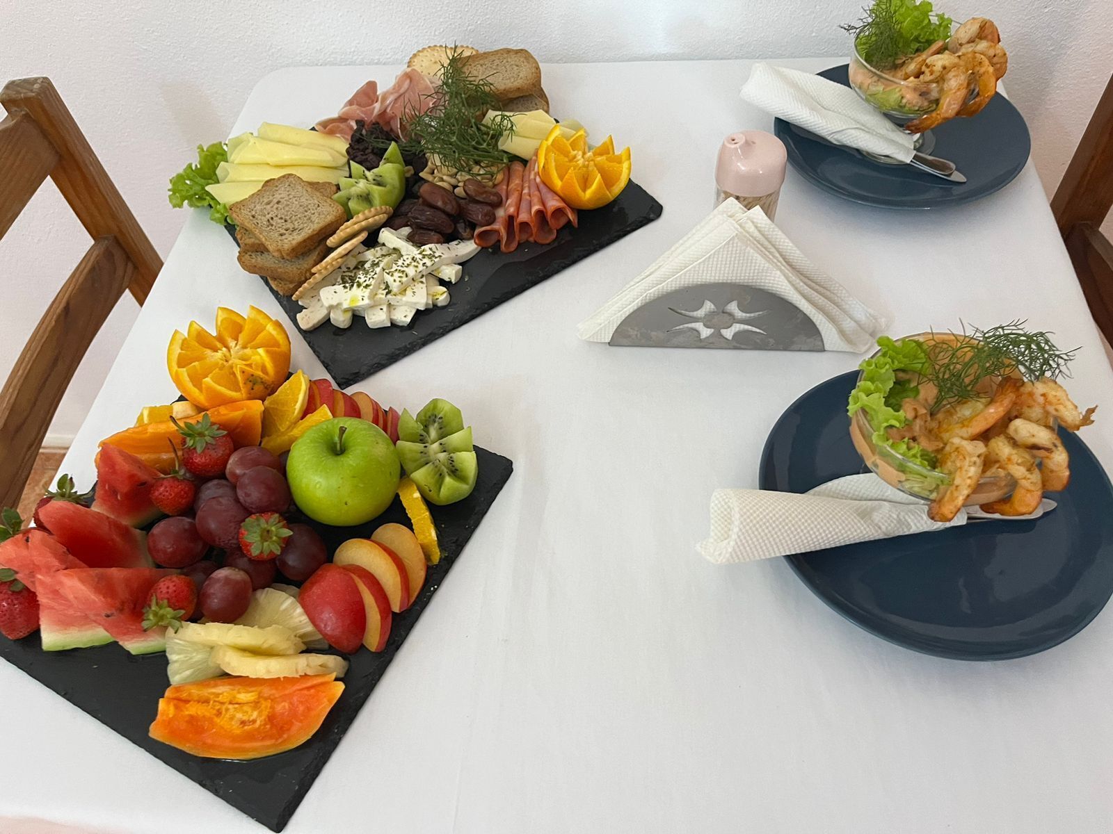 A table with various food platters including fruits, cheeses, and seafood.
