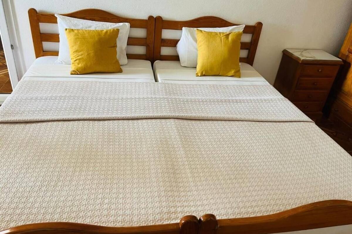 A bed with a wooden headboard, two pillows, and a white bedspread.
