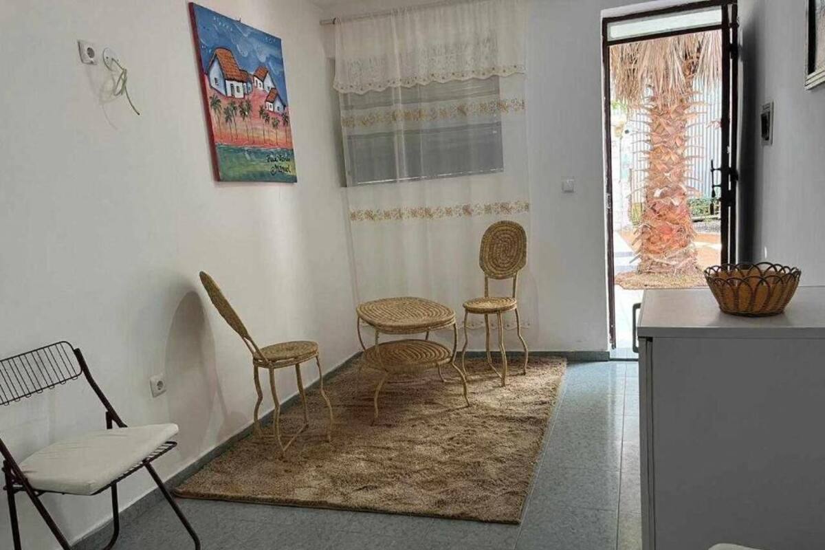 A room with a large window, a woven rug, and wicker furniture.