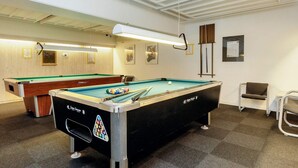 A pool table with a black tablecloth and a pool cue, a second pool table in the background, and a chair to the right. - 4 Person Holiday Park Home in Faaborg (Faaborg)