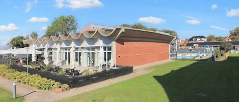 A building with a brick exterior and a white facade, featuring outdoor seating and umbrellas.