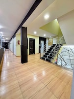 Un pasillo de hotel con una escalera y un extintor en la pared.