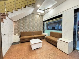 Un interior moderno con una pared de piedra, un sofá marrón, una mesa de centro blanca y un ventilador de techo.