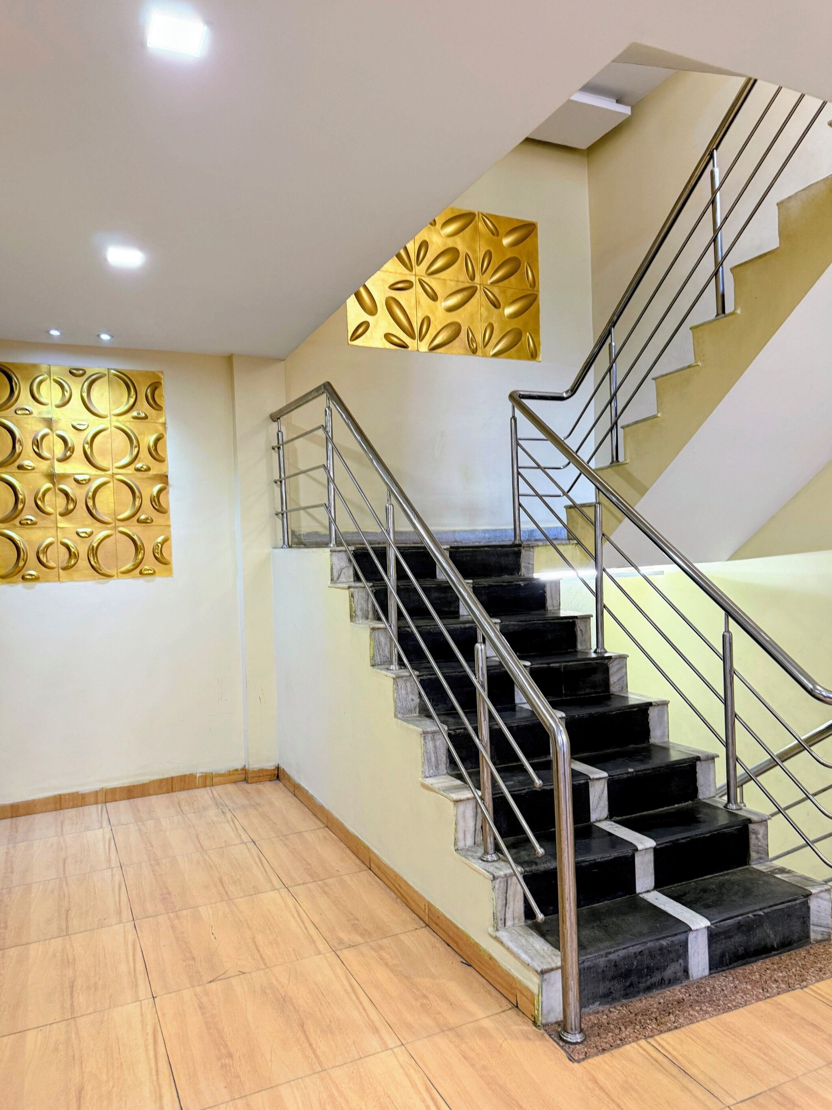 A modern staircase with metal railings, a patterned wall, and a wooden floor.