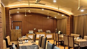 Un ristorante con lunghe tavolate, sedie, ventilatori a soffitto e pareti in legno.