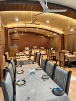 Un restaurante con mesas largas, sillas, ventiladores de techo y paneles de madera.