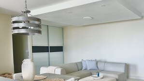 Un salon moderne avec un canapé, un pouf et un coin repas.