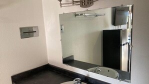 A bathroom with a large mirror, a sink, and a towel rack. - Arrowhead Inn (New Salem)