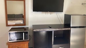 A room with a bed, a television mounted on the wall, a microwave, and a refrigerator. - Arrowhead Inn (New Salem)