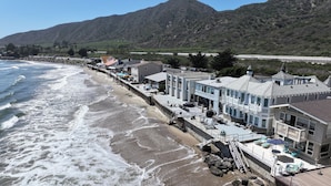 Ein Hotel an der Küste mit Blick auf den Strand, einem Poolbereich und einem Bergpanorama.