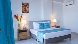 Quarto com uma cama, duas mesas de cabeceira, ar-condicionado fixado na parede e um quadro.