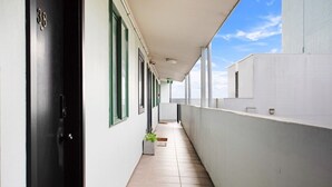A narrow corridor with a black door marked "38" and a white wall with windows.