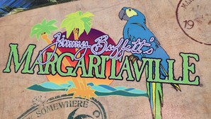 Un logo représentant un perroquet et des palmiers, ainsi que le texte « Jimmy Buffett’s Margaritaville ».