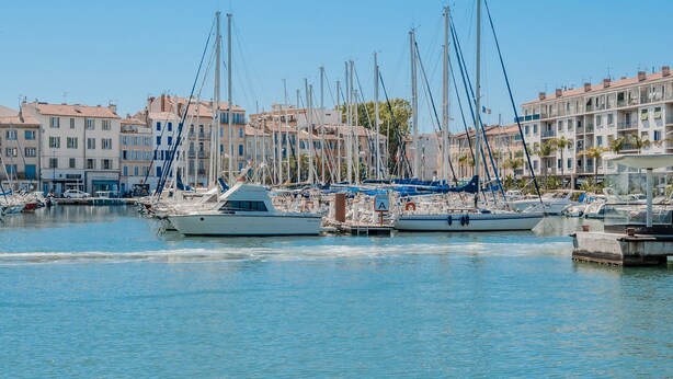 A marina with boats docked, surrounded by multi-story buildings with balconies. - Sun & Colors studio - 100m of harbour (La Seyne-sur-Mer)