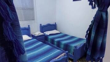 A room with three blue beds, a patterned floor, and a small wall-mounted picture.