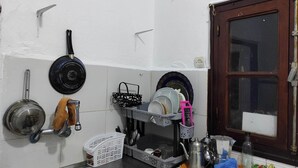 Een keuken met een spoelbak, een fornuis en diverse keukengerei en servies.