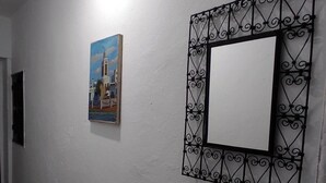 Een gang met een patroon vloer, een lijst met een foto van een gebouw, en een decoratieve spiegel.
