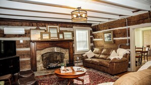 Una sala de estar acogedora con chimenea, sofá de cuero y piso de madera.