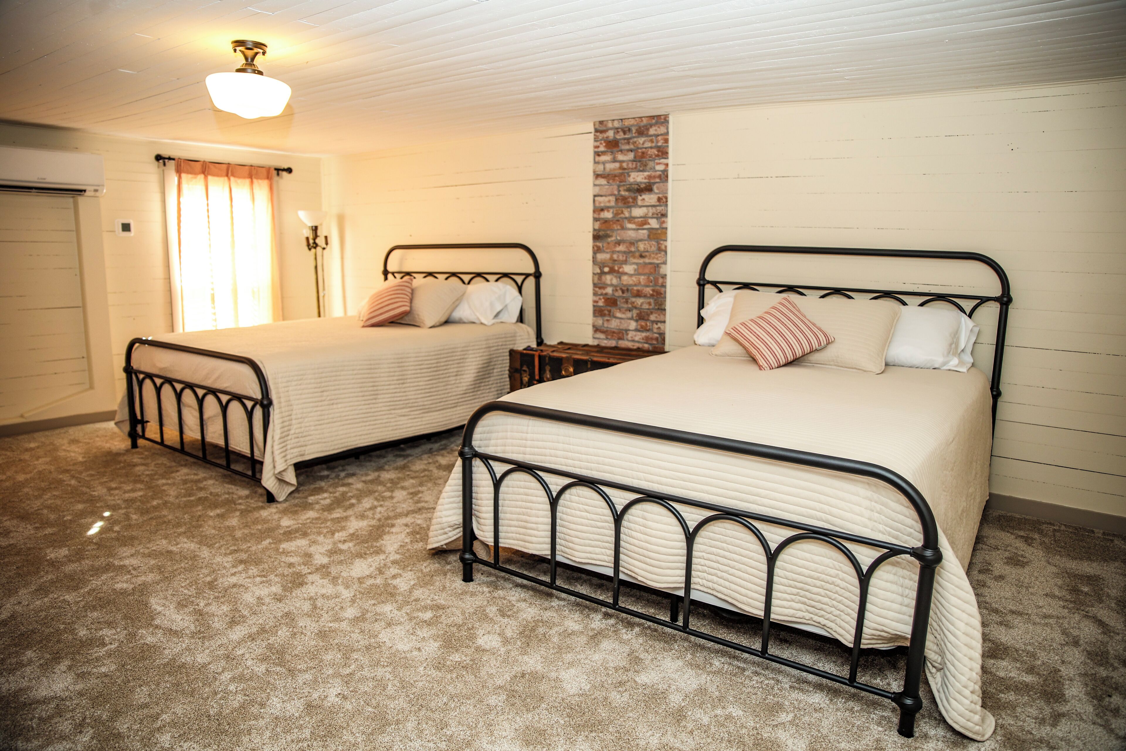 Un dormitorio con dos camas, una pared de ladrillo decorativa y un ventilador de techo.