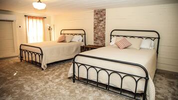 Un dormitorio con dos camas, una pared de ladrillo decorativa y un ventilador de techo.