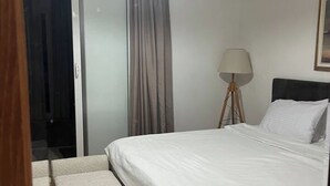 Une chambre d’hôtel avec un lit, une lampe et une porte coulissante.