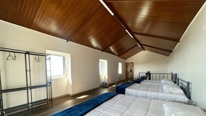 Ein Schlafzimmer mit zwei Betten, Holzboden, einem Metallschrank und einer schrägen Decke.